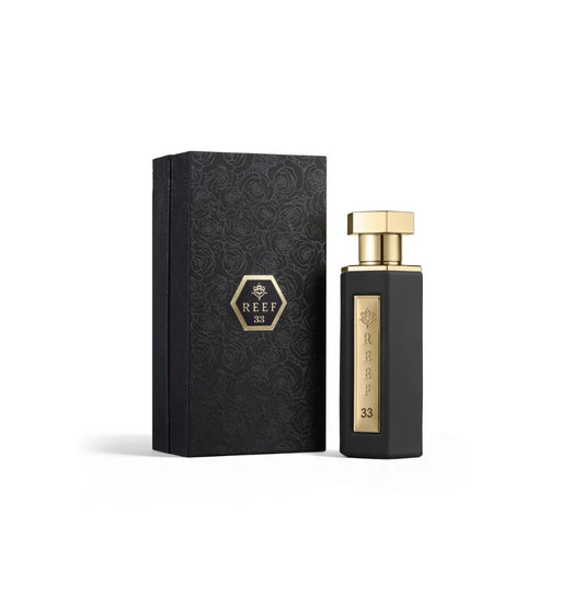 A black rectangular perfume bottle with a gold cap stands next to its matching black patterned box on a clean white background. The bottle features a vertical gold label with the brand name 'REEF 1978' and the number '33'.